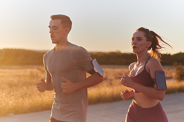 Image showing A handsome young couple running together during the early morning hours, with the mesmerizing sunrise casting a warm glow, symbolizing their shared love and vitality