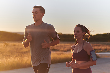 Image showing A handsome young couple running together during the early morning hours, with the mesmerizing sunrise casting a warm glow, symbolizing their shared love and vitality