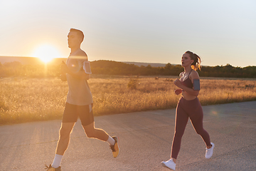 Image showing A handsome young couple running together during the early morning hours, with the mesmerizing sunrise casting a warm glow, symbolizing their shared love and vitality