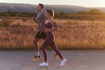 Image showing A handsome young couple running together during the early morning hours, with the mesmerizing sunrise casting a warm glow, symbolizing their shared love and vitality