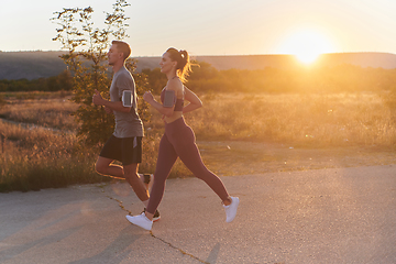 Image showing A handsome young couple running together during the early morning hours, with the mesmerizing sunrise casting a warm glow, symbolizing their shared love and vitality