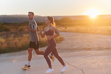 Image showing A handsome young couple running together during the early morning hours, with the mesmerizing sunrise casting a warm glow, symbolizing their shared love and vitality