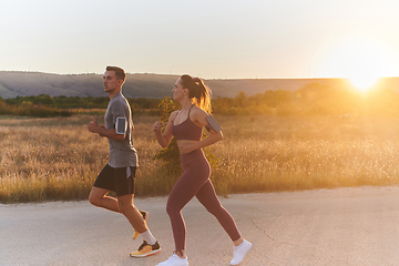 Image showing A handsome young couple running together during the early morning hours, with the mesmerizing sunrise casting a warm glow, symbolizing their shared love and vitality