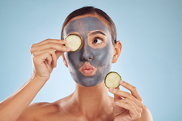 Image showing Face, cucumber and mask for beauty with a woman in studio on a blue background for antiaging skincare. Facial, idea and pout with an attractive young female holding a vegetable for natural treatment