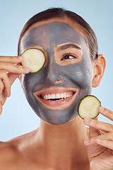 Image showing Smile, cucumber and mask for beauty with a woman in studio on a blue background for antiaging skincare. Face, thinking and antioxidants with an attractive young female person posing for treatment