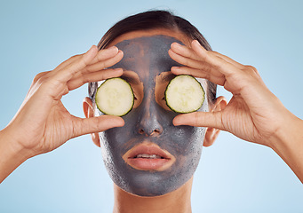 Image showing Face mask, skincare and woman with cucumber on eyes for beauty in studio isolated on a blue background. Cosmetics, model and clay facial treatment with fruit, food and dermatology, health or wellness
