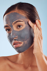 Image showing Face mask, charcoal and beauty of woman as self care, cosmetic or facial treatment isolated in blue studio background. Skin, skincare and young female person clean, hydration and dermatology cream