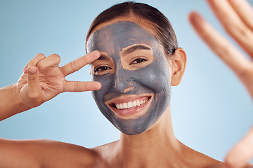 Image showing Woman, face mask and selfie in charcoal skincare and facial profile picture on studio blue background. Photography, peace and v sign of beauty influencer or person portrait, collagen and dermatology