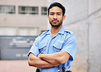 Image showing Portrait, man and security guard with arms crossed for police service, protection and safety in city. Law enforcement, bodyguard and serious asian male officer in blue uniform outdoor for town patrol