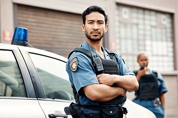 Image showing Asian man, police and arms crossed in city for law enforcement, protection or street safety. Portrait of serious male person, security guard or cop ready for justice or crime on patrol in urban town