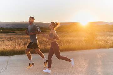 Image showing A handsome young couple running together during the early morning hours, with the mesmerizing sunrise casting a warm glow, symbolizing their shared love and vitality