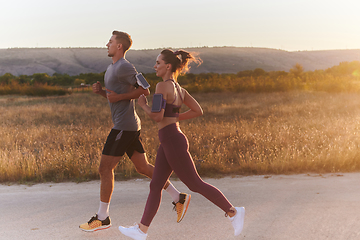 Image showing A handsome young couple running together during the early morning hours, with the mesmerizing sunrise casting a warm glow, symbolizing their shared love and vitality