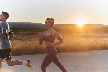 Image showing A handsome young couple running together during the early morning hours, with the mesmerizing sunrise casting a warm glow, symbolizing their shared love and vitality