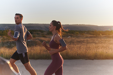 Image showing A handsome young couple running together during the early morning hours, with the mesmerizing sunrise casting a warm glow, symbolizing their shared love and vitality