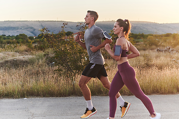 Image showing A handsome young couple running together during the early morning hours, with the mesmerizing sunrise casting a warm glow, symbolizing their shared love and vitality