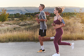 Image showing A handsome young couple running together during the early morning hours, with the mesmerizing sunrise casting a warm glow, symbolizing their shared love and vitality