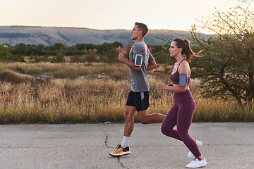 Image showing A handsome young couple running together during the early morning hours, with the mesmerizing sunrise casting a warm glow, symbolizing their shared love and vitality