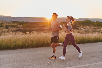 Image showing A handsome young couple running together during the early morning hours, with the mesmerizing sunrise casting a warm glow, symbolizing their shared love and vitality