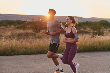 Image showing A handsome young couple running together during the early morning hours, with the mesmerizing sunrise casting a warm glow, symbolizing their shared love and vitality