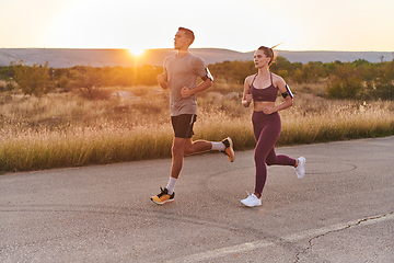 Image showing A handsome young couple running together during the early morning hours, with the mesmerizing sunrise casting a warm glow, symbolizing their shared love and vitality