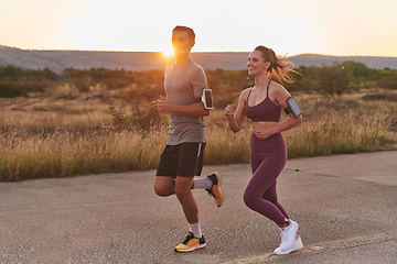 Image showing A handsome young couple running together during the early morning hours, with the mesmerizing sunrise casting a warm glow, symbolizing their shared love and vitality