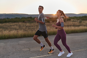 Image showing A handsome young couple running together during the early morning hours, with the mesmerizing sunrise casting a warm glow, symbolizing their shared love and vitality