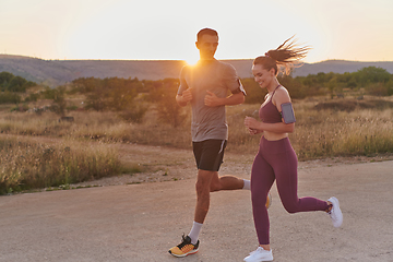 Image showing A handsome young couple running together during the early morning hours, with the mesmerizing sunrise casting a warm glow, symbolizing their shared love and vitality