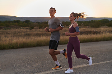 Image showing A handsome young couple running together during the early morning hours, with the mesmerizing sunrise casting a warm glow, symbolizing their shared love and vitality