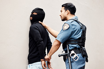 Image showing Man, police and handcuffs on gangster for arrest, crime or justice in theft, robbery or violence. Male person, officer or security guard cuffing hands of robber, thief or criminal against the wall