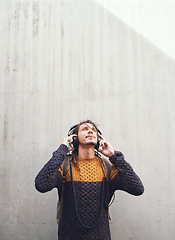 Image showing Man is listening to music, student with headphones on university campus and future mindset against wall background. Gen z, education and male person at college, mockup space and podcast streaming