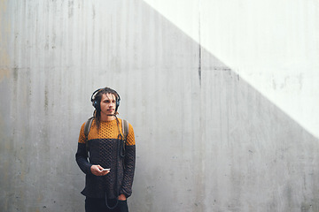Image showing Man, student and smartphone with headphones and music on university campus, future mindset against wall background. Gen z, education and male person at college, mockup space and listen to podcast
