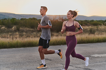 Image showing A handsome young couple running together during the early morning hours, with the mesmerizing sunrise casting a warm glow, symbolizing their shared love and vitality