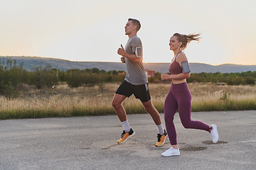 Image showing A handsome young couple running together during the early morning hours, with the mesmerizing sunrise casting a warm glow, symbolizing their shared love and vitality