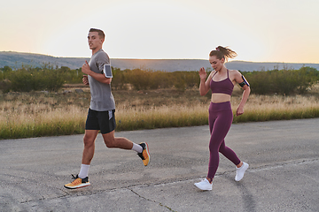 Image showing A handsome young couple running together during the early morning hours, with the mesmerizing sunrise casting a warm glow, symbolizing their shared love and vitality