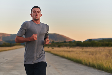 Image showing A young handsome man running in the early morning hours, driven by his commitment to health and fitness