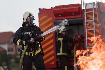 Image showing Firefighters using water fog type fire extinguisher to fighting with the fire flame to control fire not to spreading out. Firefighter industrial and public safety concept.