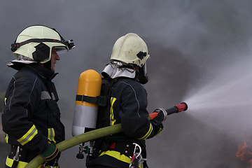 Image showing Firefighters using water fog type fire extinguisher to fighting with the fire flame to control fire not to spreading out. Firefighter industrial and public safety concept.