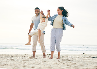 Image showing Beach, family and holding hands outdoor for travel, freedom and bond in nature together. Love, fun and boy child with young parents at the sea with swing game, playing and happy on ocean holiday trip