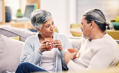 Image showing Coffee, conversation and senior couple on a sofa for bond, discussion or sharing gossip in their home. Love, tea and old people relax on couch for break, speaking or did you know drama in living room