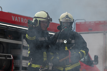 Image showing Firefighters using water fog type fire extinguisher to fighting with the fire flame to control fire not to spreading out. Firefighter industrial and public safety concept.