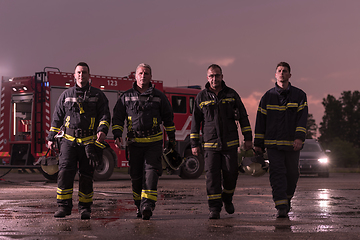 Image showing Brave Firefighters Team Walking to the Camera. In Background Paramedics and Firemen Rescue Team Fight Fire in Car Accident, Insurance and Save Peoples Lives concept.