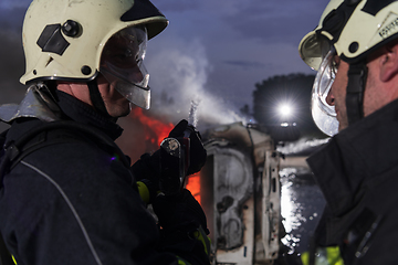 Image showing Firefighters using water fire extinguisher to fighting with the fire flame in car accident. Firefighter industrial and public safety concept rescue in night.