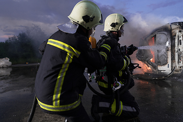 Image showing Firefighters using water fire extinguisher to fighting with the fire flame in car accident. Firefighter industrial and public safety concept rescue in night.