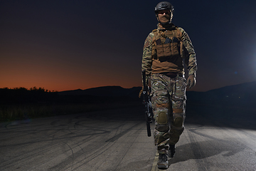 Image showing A professional soldier in full military gear striding through the dark night as he embarks on a perilous military mission