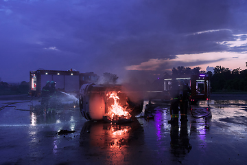 Image showing Firefighters using water fire extinguisher to fighting with the fire flame in car accident. Firefighter industrial and public safety concept rescue in night.