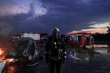 Image showing Portrait of a heroic fireman in a protective suit. Firefighter in fire fighting or car accident rescue operation in dusk or night.