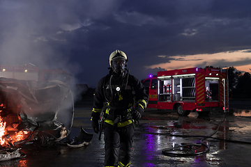 Image showing Portrait of a heroic fireman in a protective suit. Firefighter in fire fighting or car accident rescue operation in dusk or night.