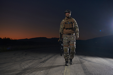 Image showing A professional soldier in full military gear striding through the dark night as he embarks on a perilous military mission