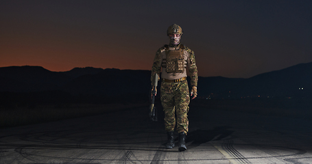 Image showing A professional soldier in full military gear striding through the dark night as he embarks on a perilous military mission