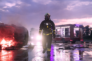 Image showing Portrait of a heroic fireman in a protective suit. Firefighter in fire fighting or car accident rescue operation in dusk or night.